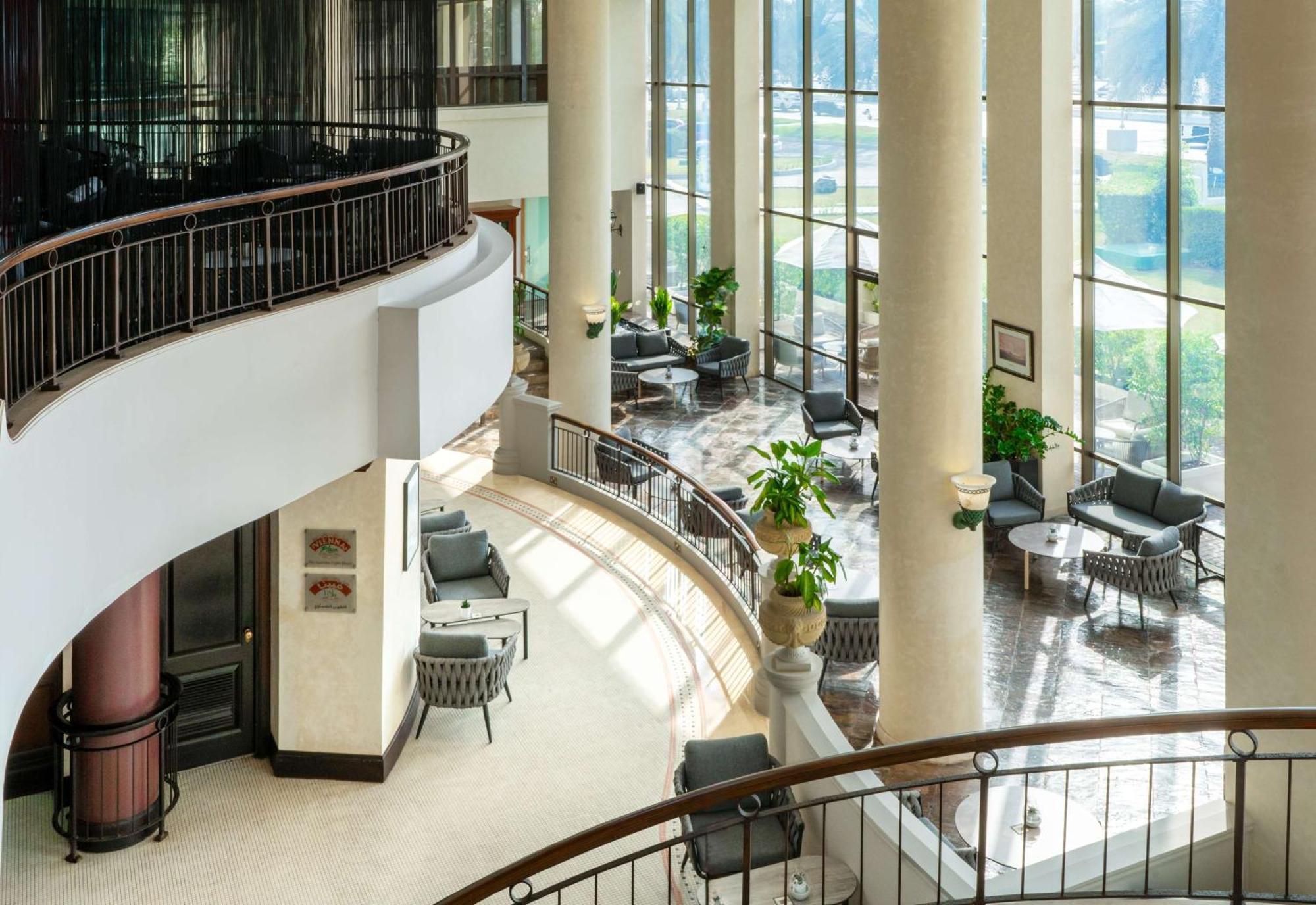 Radisson Blu Hotel & Resort, Abu Dhabi Corniche Exterior foto The photo depicts a modern interior space, likely within a hotel or a commercial building. It features large windows that allow natural light to flood in, creating a bright and inviting atmosphere. The design includes tall columns and a curved balcon